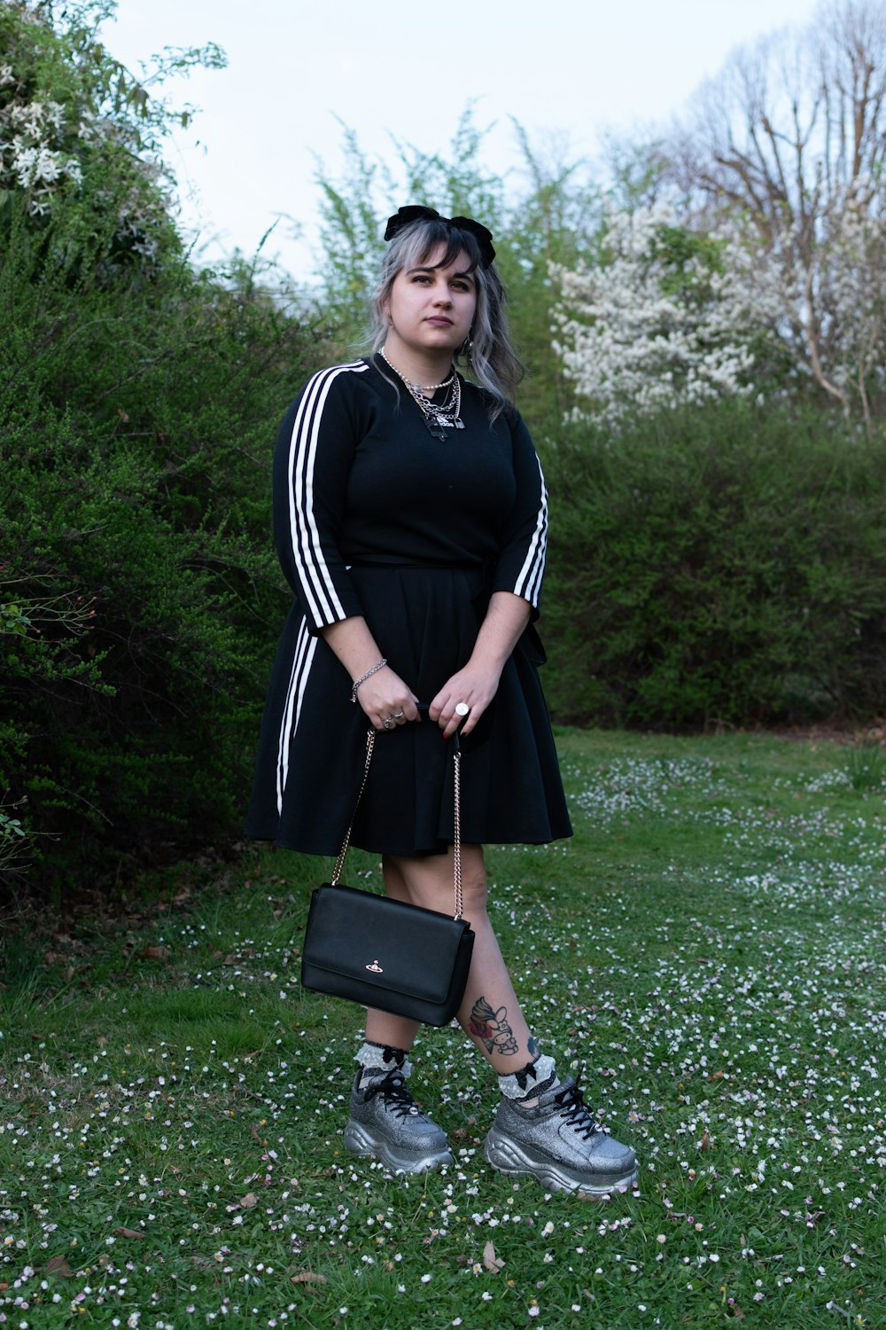 a woman in a black dress holding a black purse