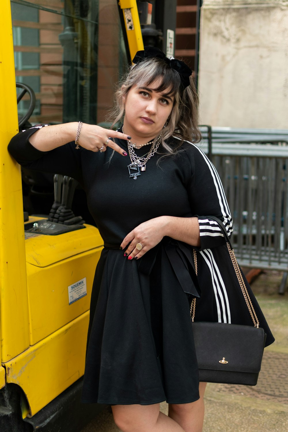 a woman in a black dress leaning against a yellow bus