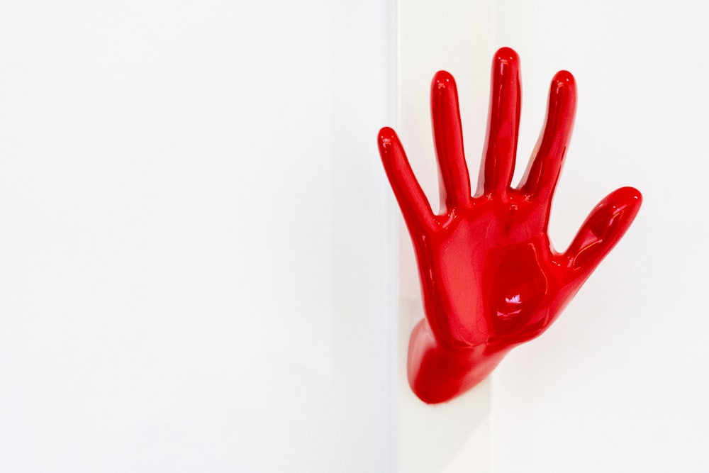 Une main rouge sur un mur blanc