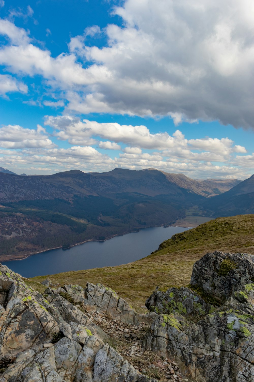 a man standing on top of a mountain next to a lake