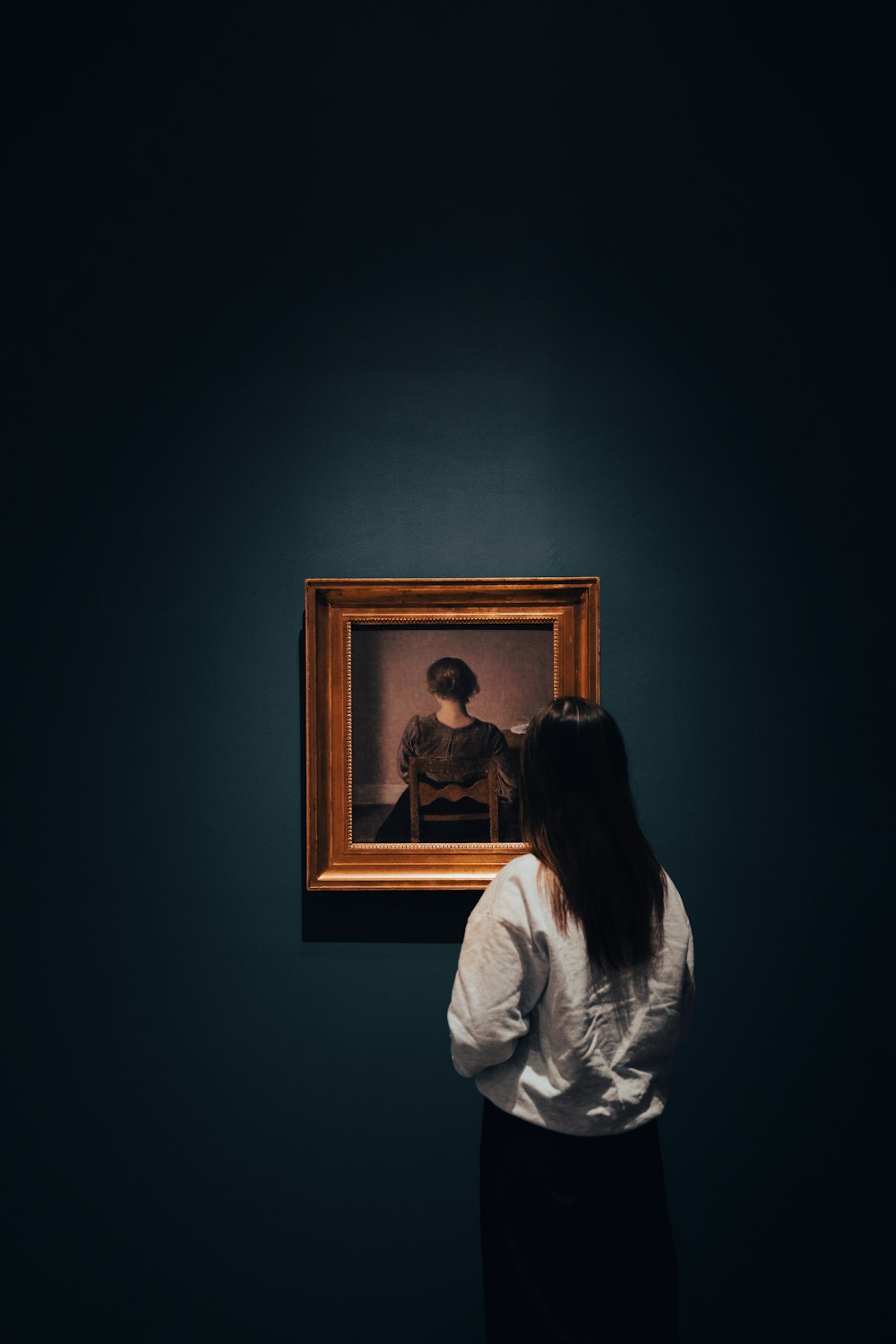 Una mujer mirando una pintura en una habitación oscura