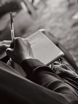 a person sitting down writing on a notebook