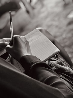 a person sitting down writing on a notebook