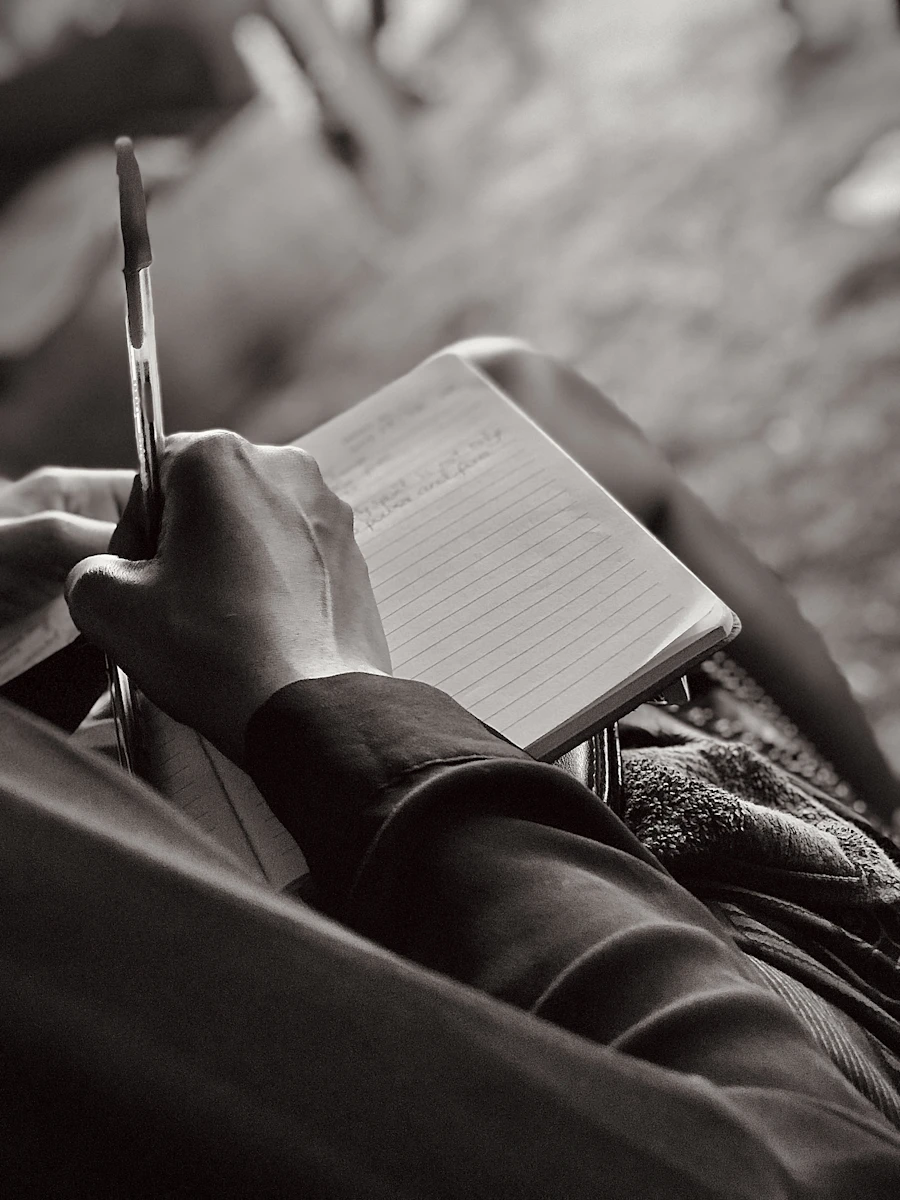 A person sitting and writing notes in a notebook — manual records and paperwork