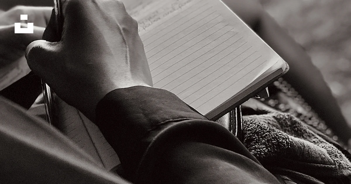 A person sitting down writing on a notebook photo – Free Grey Image on ...