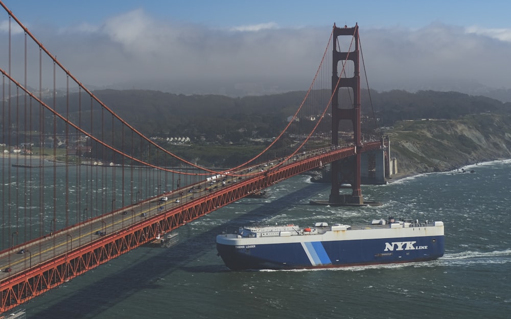 a blue and white boat in front of a bridge