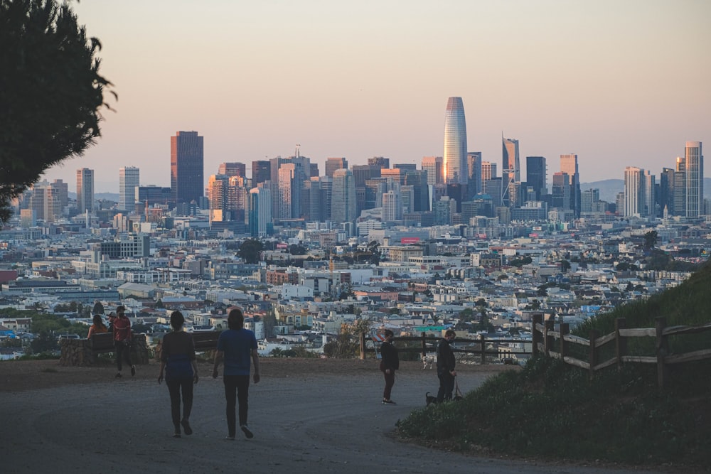 a group of people walking up a hill towards a city