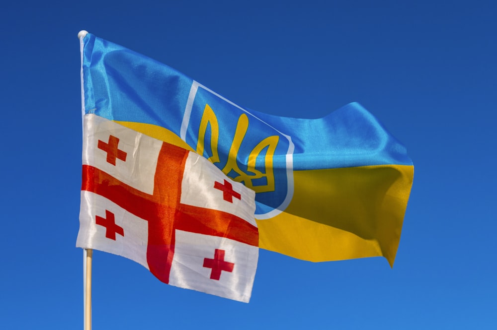 two flags flying in the wind on a sunny day