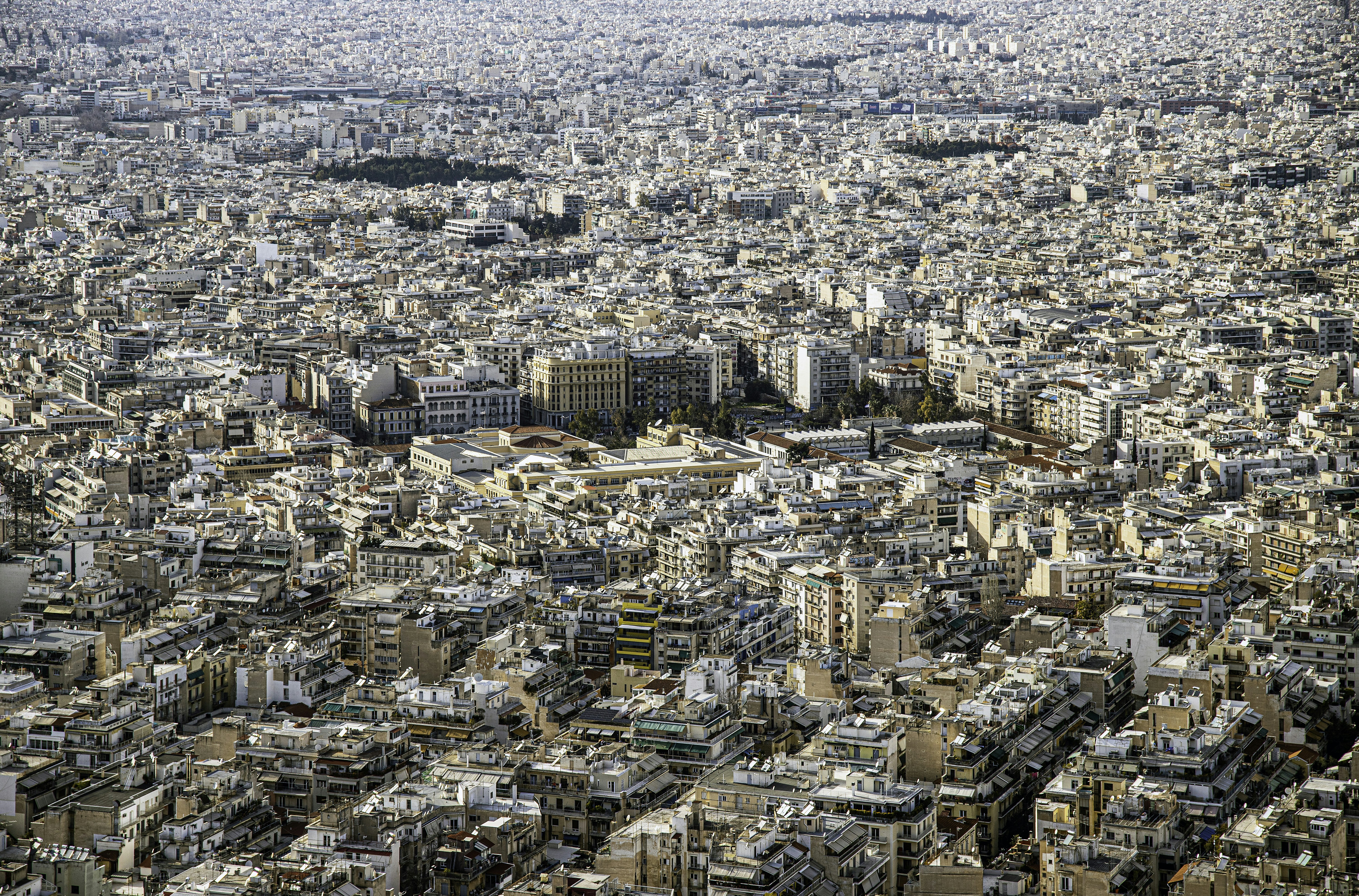 an aerial view of a city with lots of tall buildings, A view over Athens (Greece), where 3 million people live in white houses, from Lycabettus Hill.