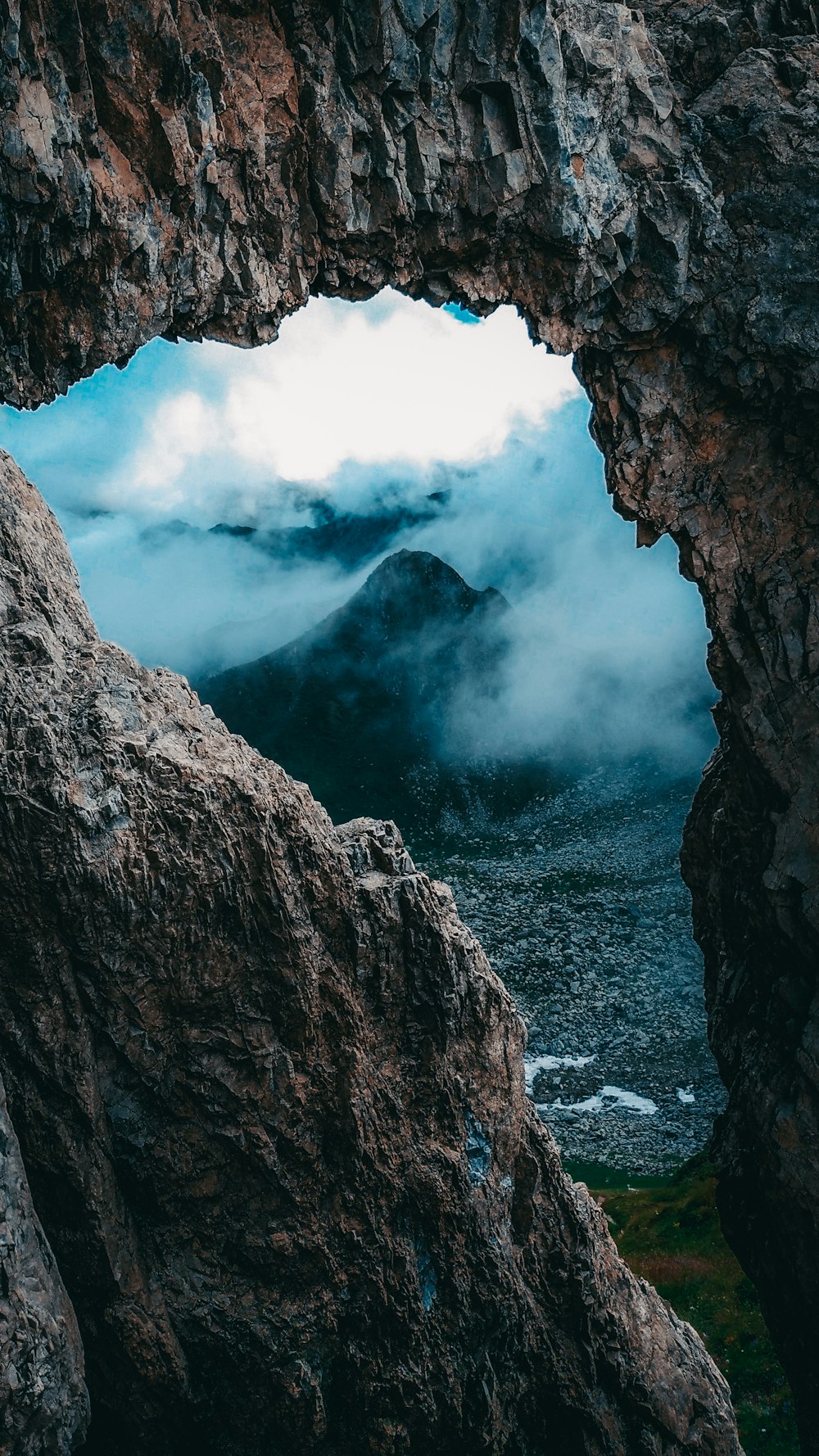 a view of a mountain through a hole in a rock