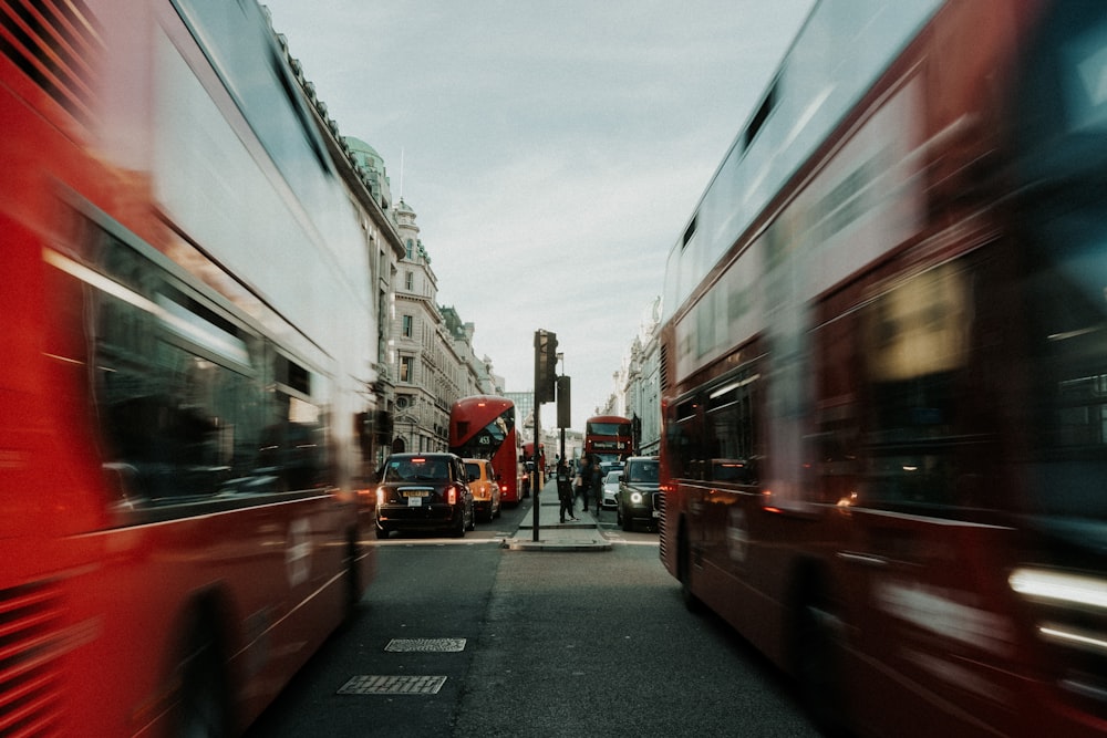 two red double decker buses driving down a street