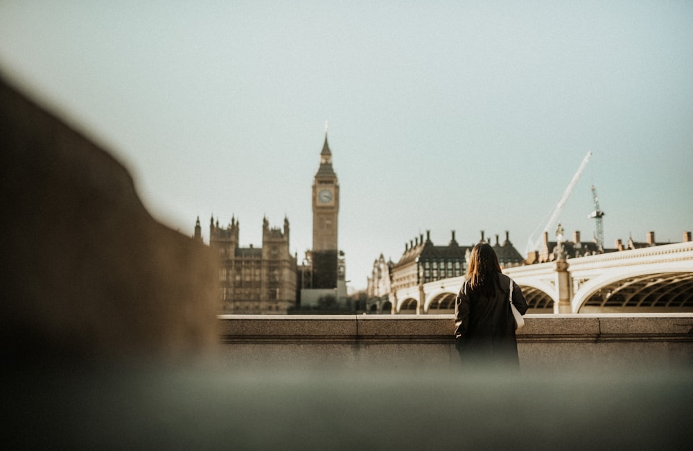 a woman standing in front of a clock tower