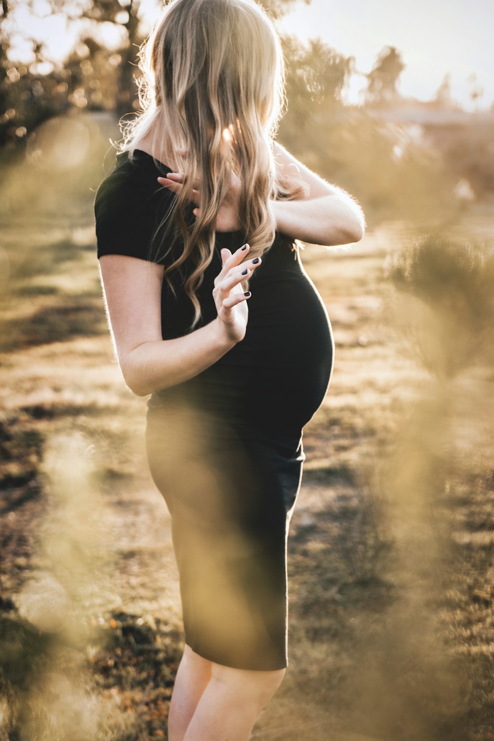 a pregnant woman in a black dress poses for a picture