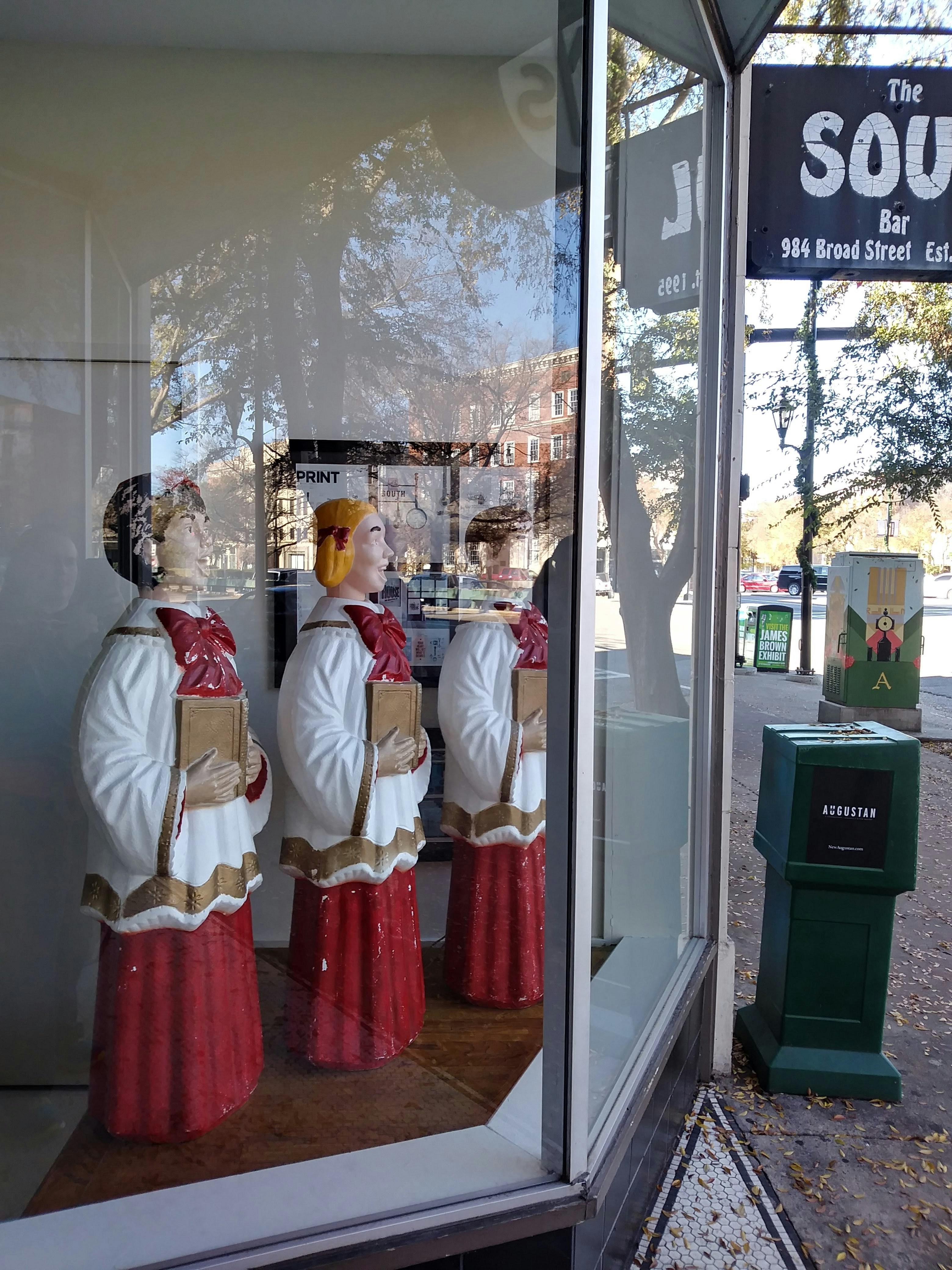 Broad street Augusta Georgia with blow mold carolers in a store window and windows reflecting street scene