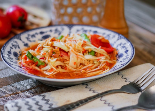 a white and blue bowl filled with pasta and vegetables