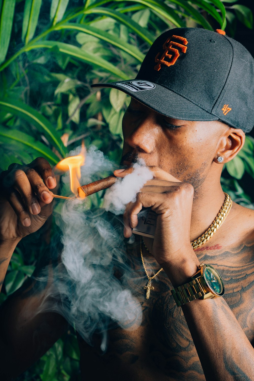 a man smoking a cigarette in front of a plant