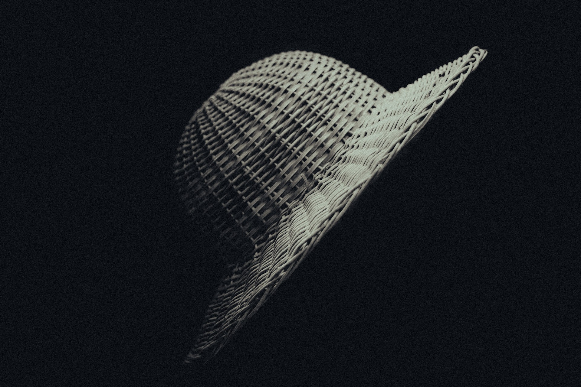 A side profile of a custom-shaped wide-brim hat, highlighting its smooth curves and natural earth-toned felt under soft natural light.