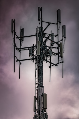 Technicians installing telecommunications equipment on a tall tower.