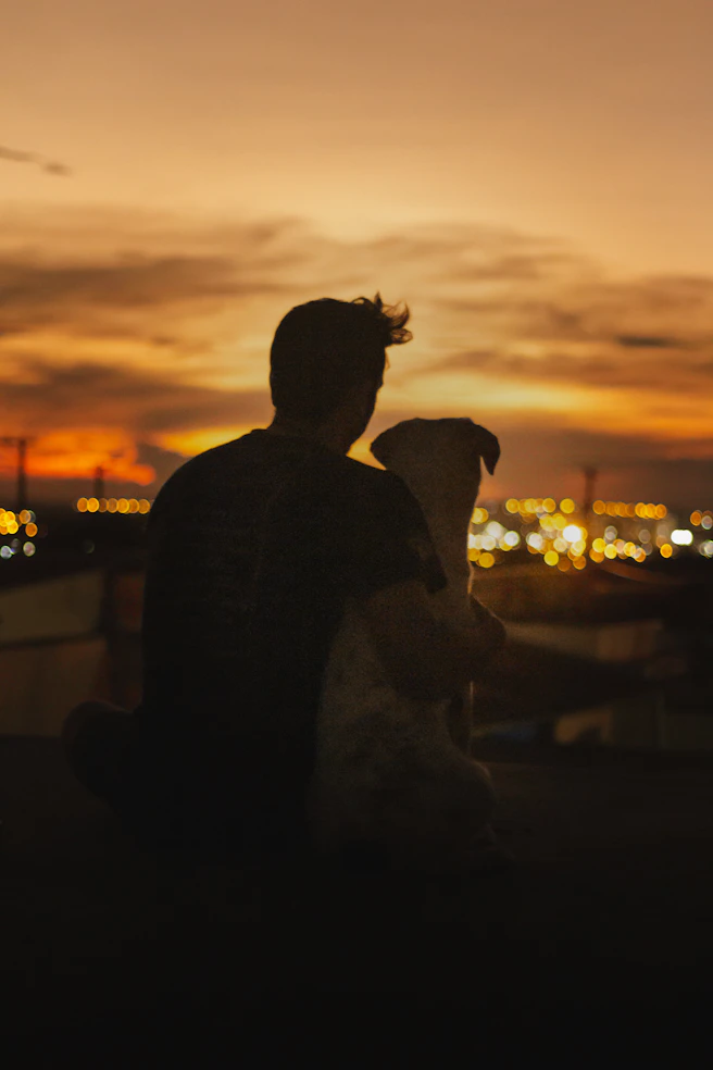 a man sitting on a ledge with a dog in his lap
