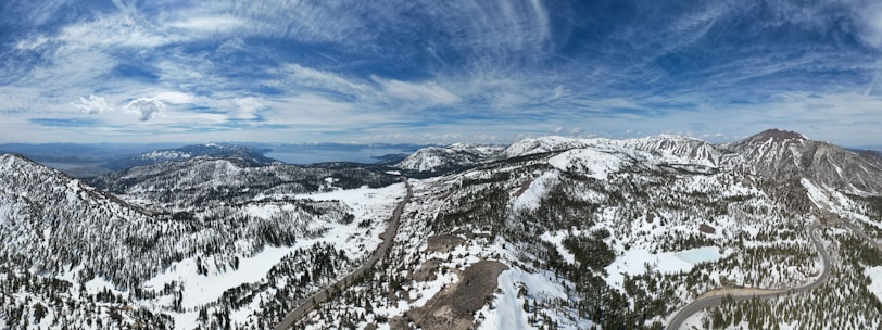 A panoramic view of snow-capped mountains with a winding road below.