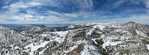 A panoramic view of the snow-capped Himalayas with a winding mountain road below.