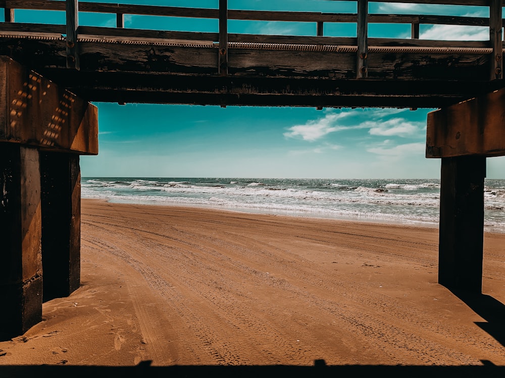 a view of a beach from under a bridge