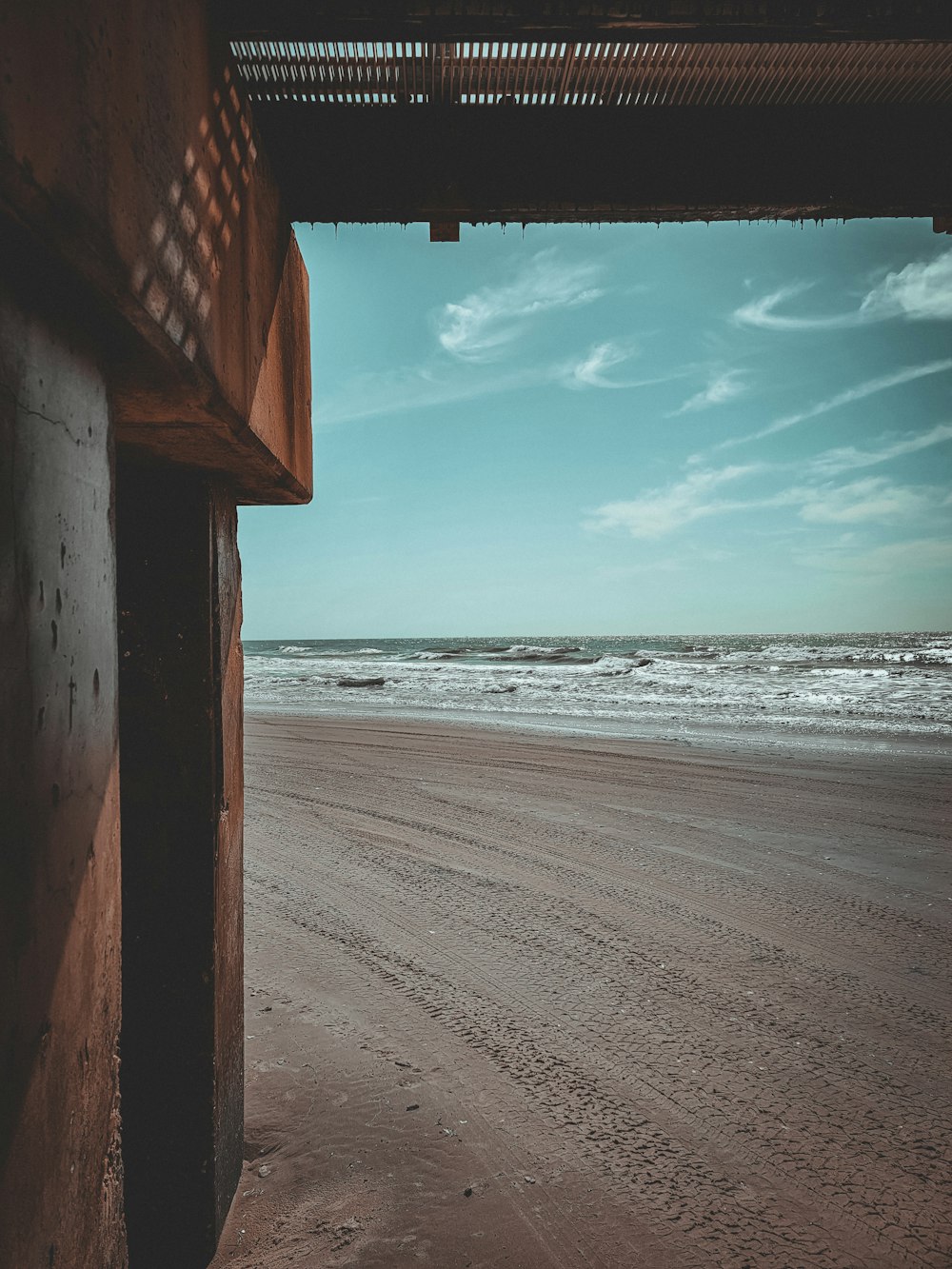 a view of a beach from under a building