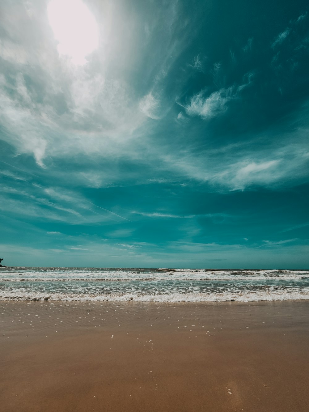 a person walking on a beach with a surfboard