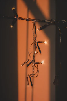 A delicate string of fairy lights draped over a minimalist wall art piece, creating a gentle glow.