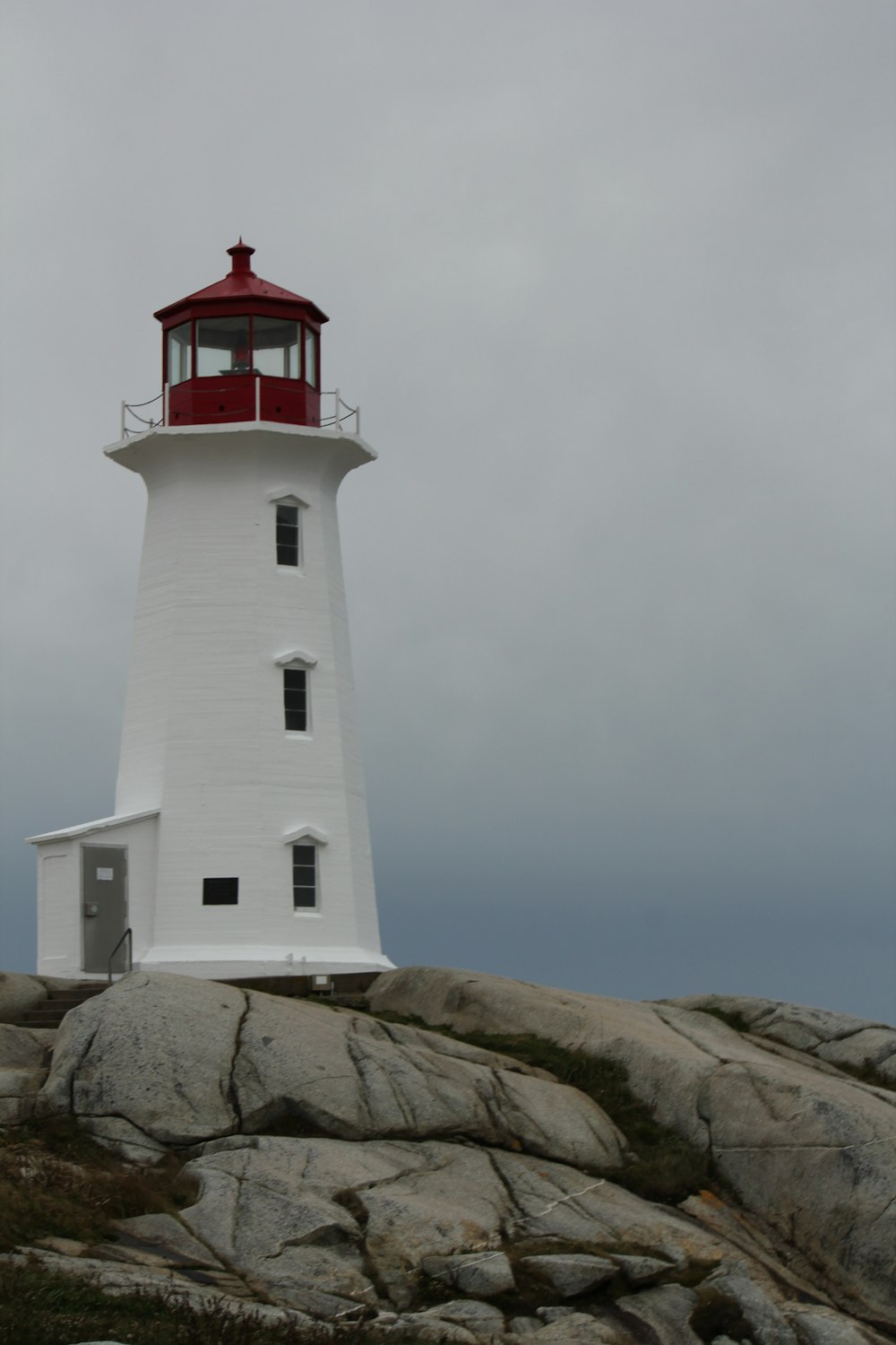 a white lighthouse with a red top on top of a rock