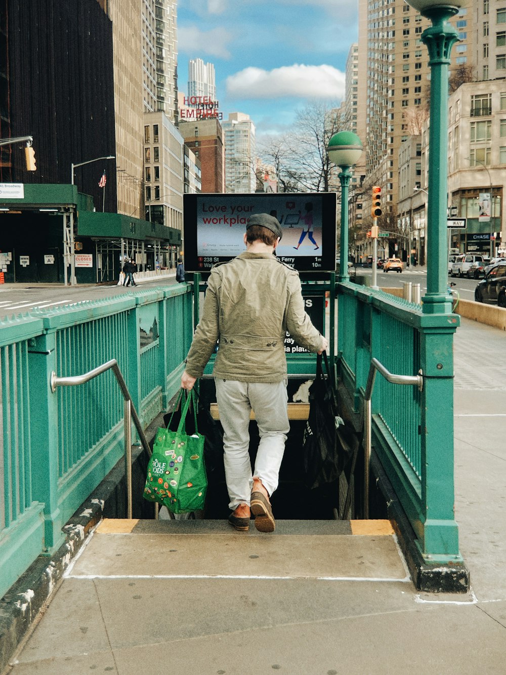 a man with a green bag walking down a sidewalk