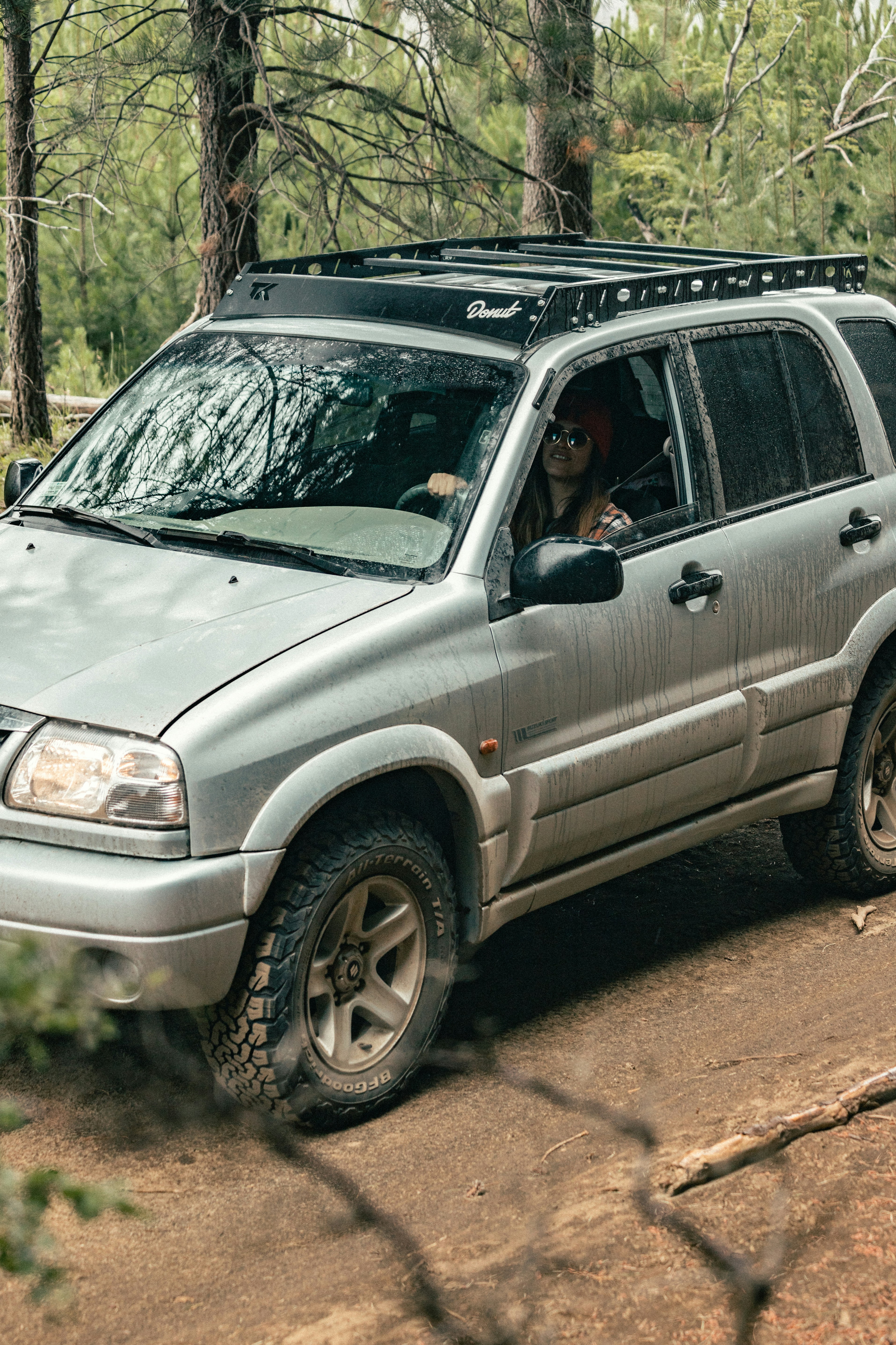 um suv prateado dirigindo através de uma floresta cheia de árvores