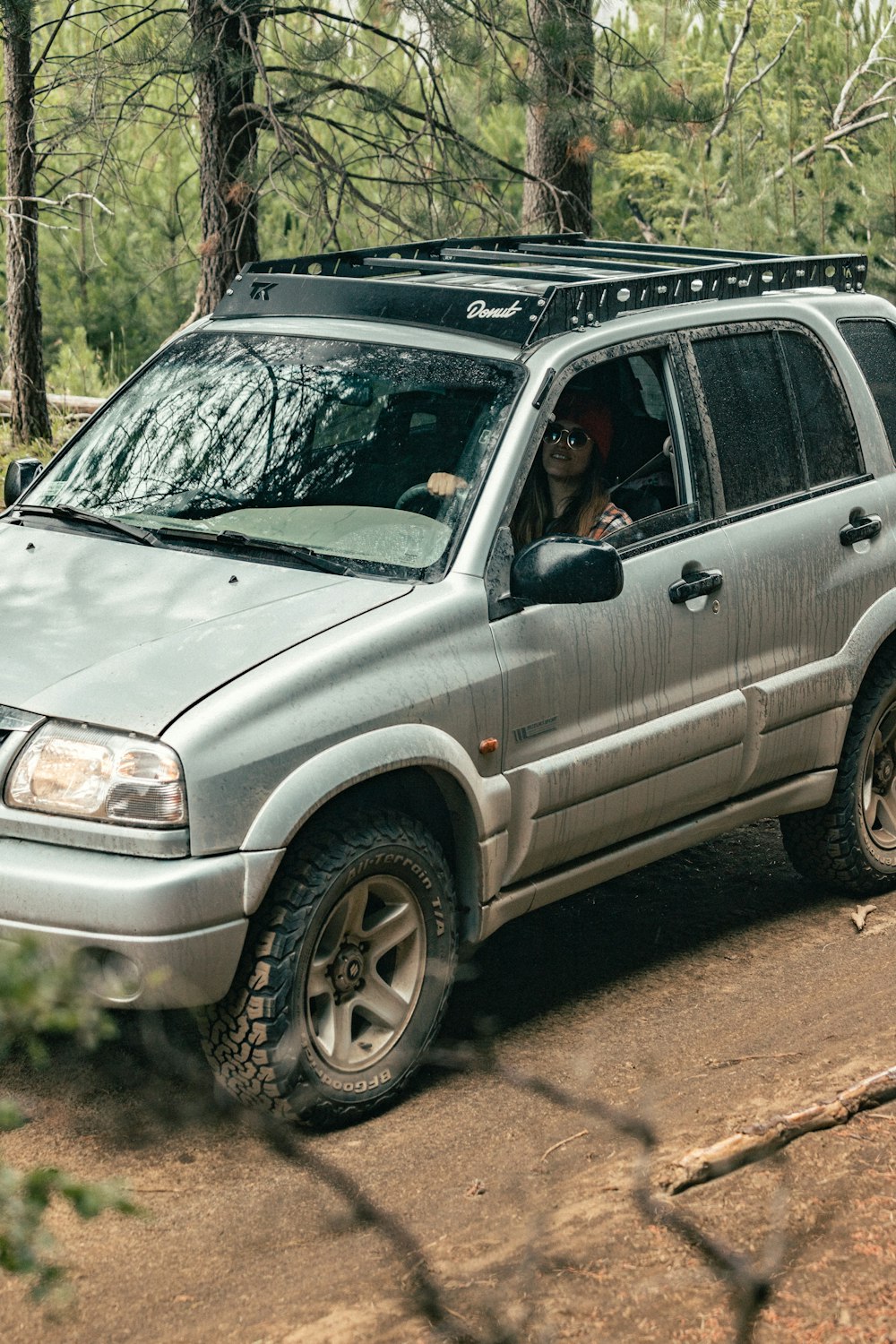 a silver suv driving through a forest filled with trees