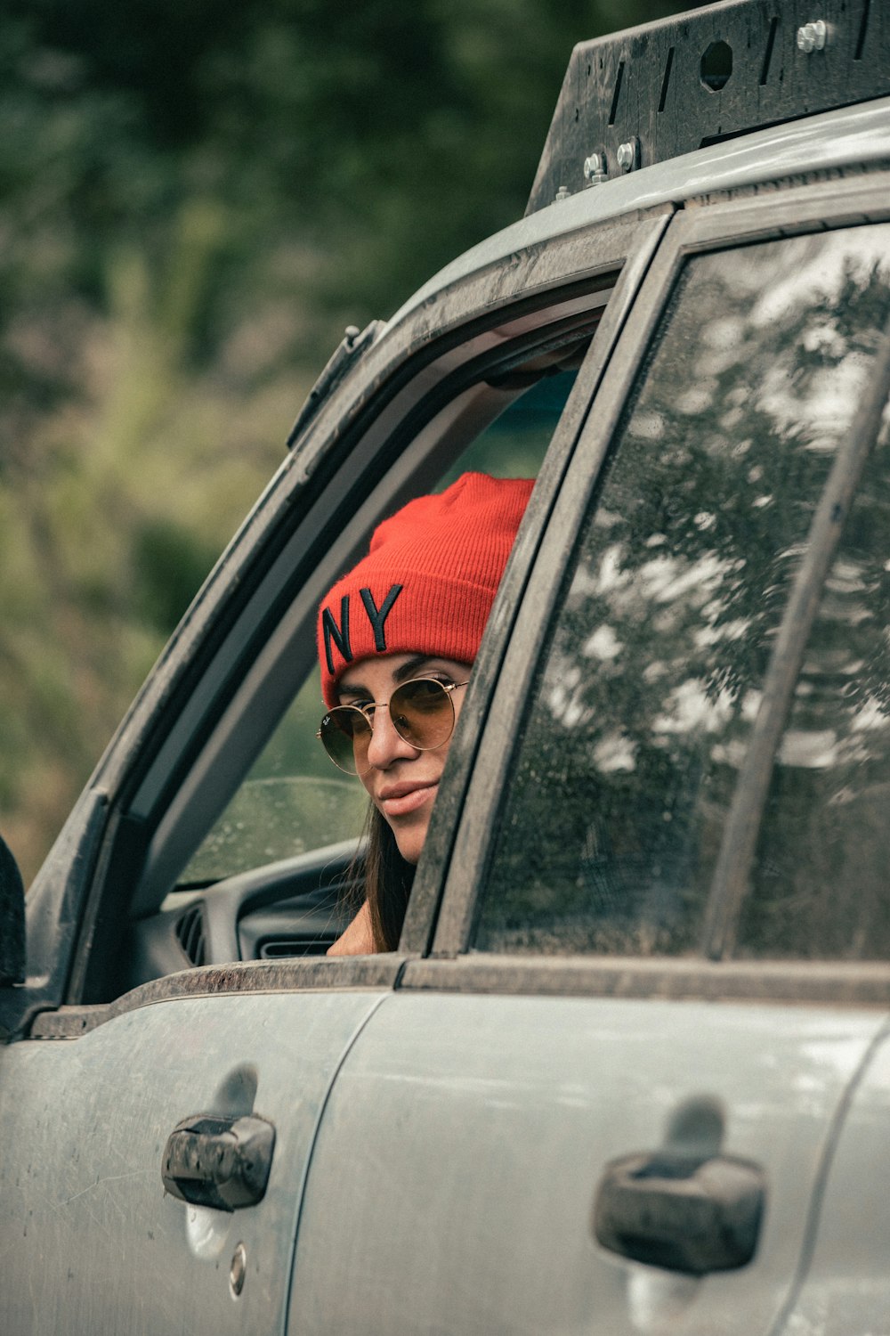 Una donna che indossa un cappello rosso e occhiali da sole seduta in una macchina