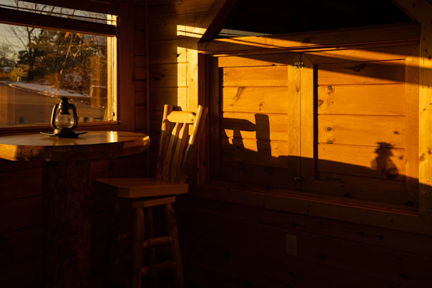 Cozy crochet blanket draped over a rustic wooden chair beside a glowing lantern.