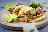 a wooden plate topped with three tacos and a lime