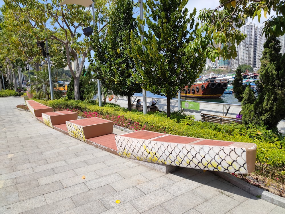 a row of benches sitting next to a lush green park