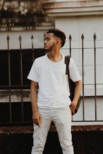 A stylish young man confidently wearing a crisp white polo shirt and jeans, standing against a minimalist urban backdrop.