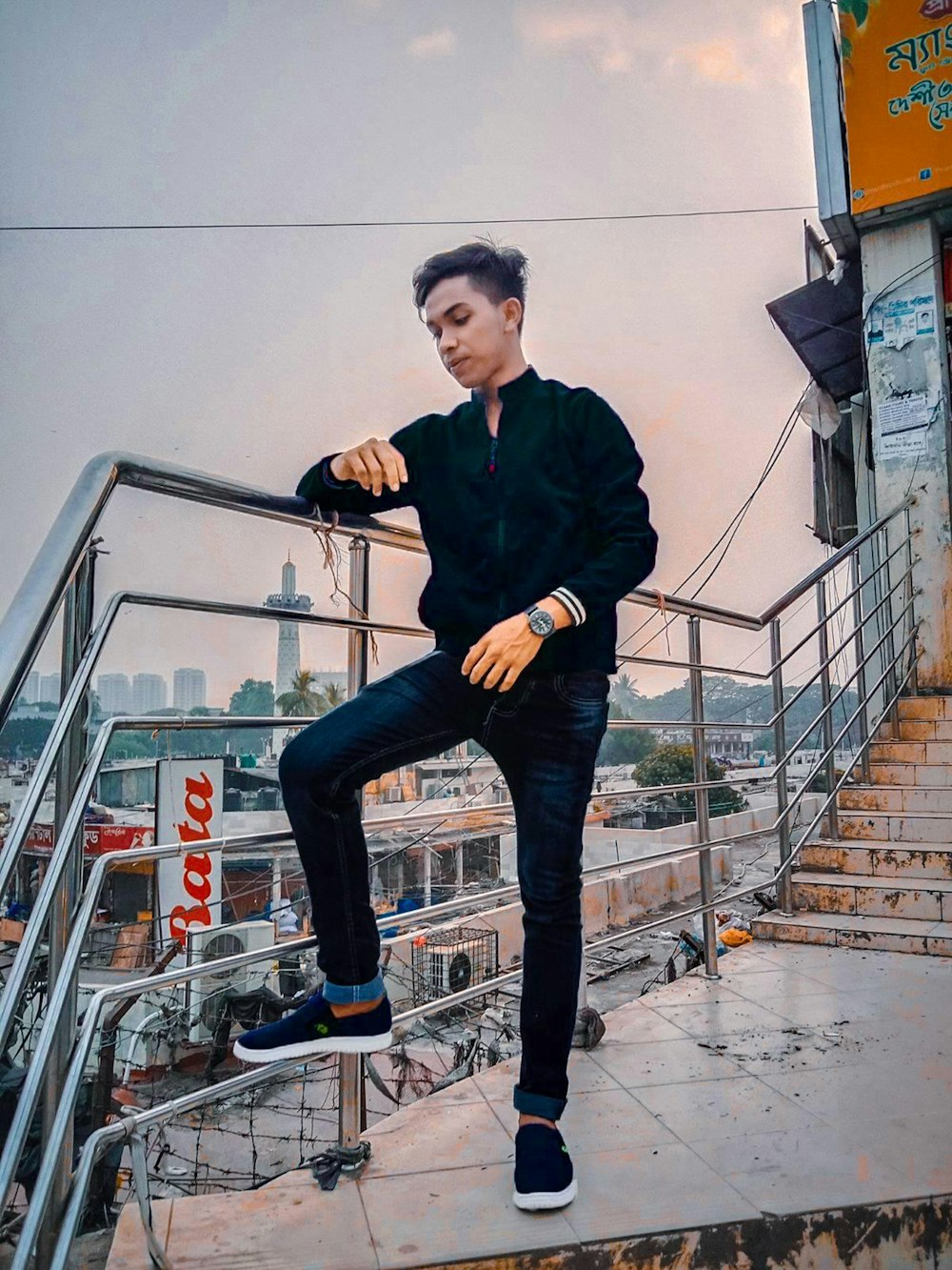 a man sitting on top of a metal hand rail