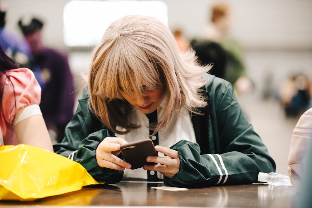 a woman sitting at a table looking at a cell phone