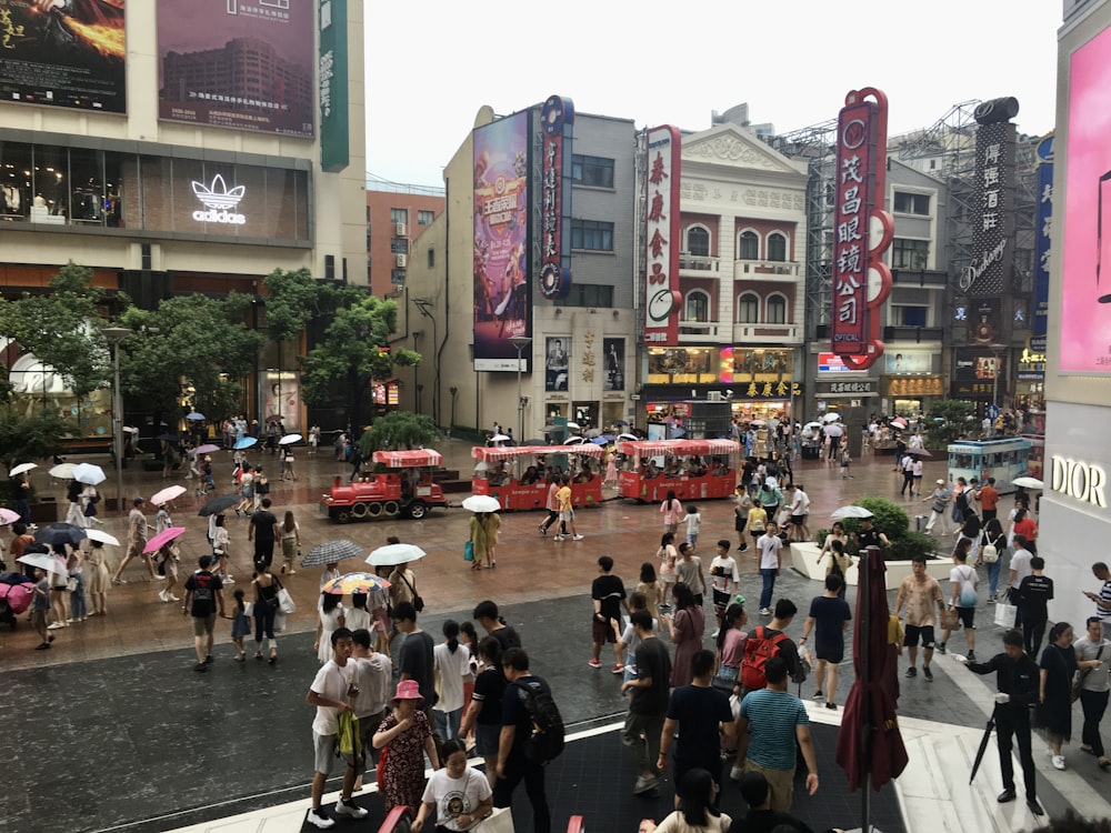 a crowd of people walking down a street next to tall buildings