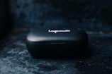 A small, black portable device case with the inscription 'Loop audio' on top, positioned against a dark and slightly textured background.