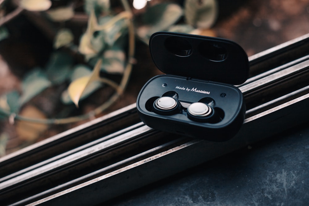 a pair of black earbuds sitting on top of a window sill