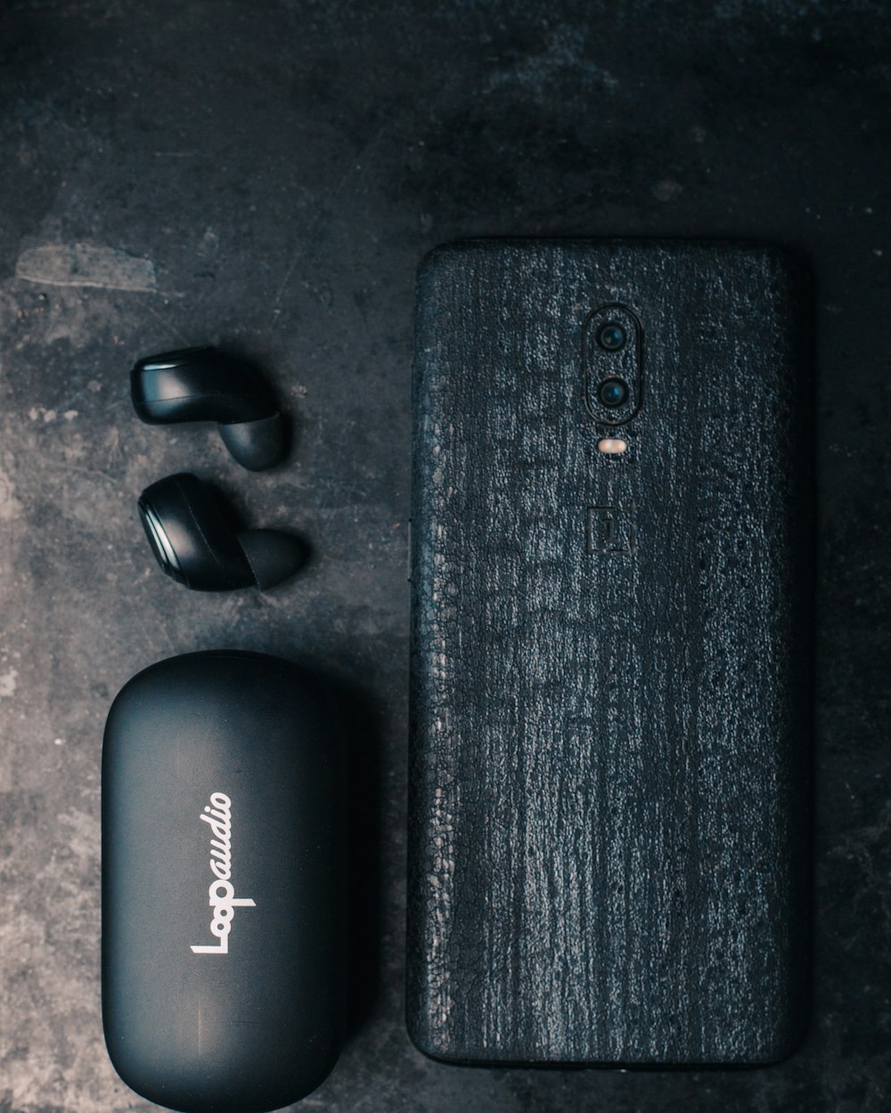 a black cell phone next to a pair of earbuds