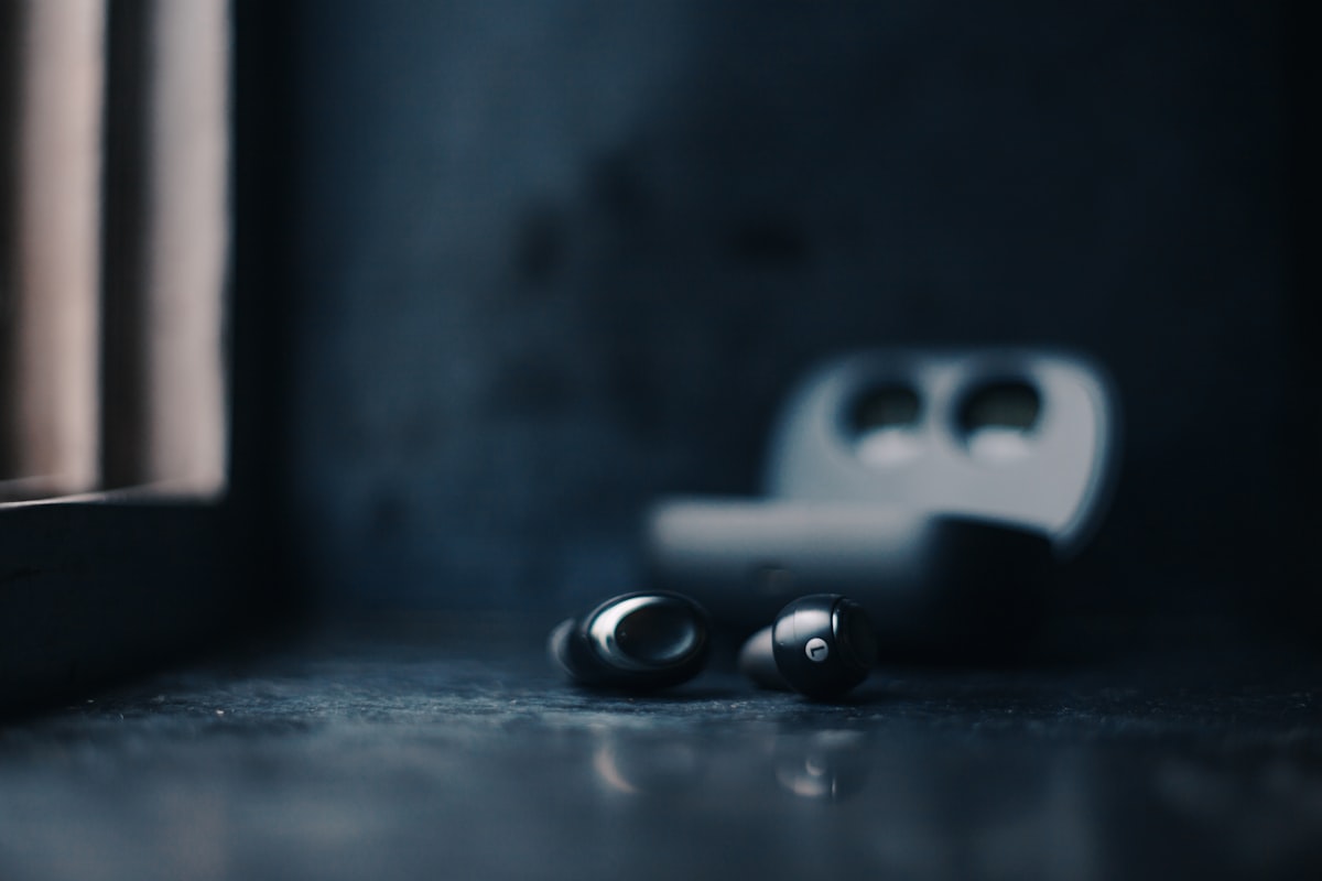 Wireless earbuds on a table by a window, soft morning light — audio practice in real life
