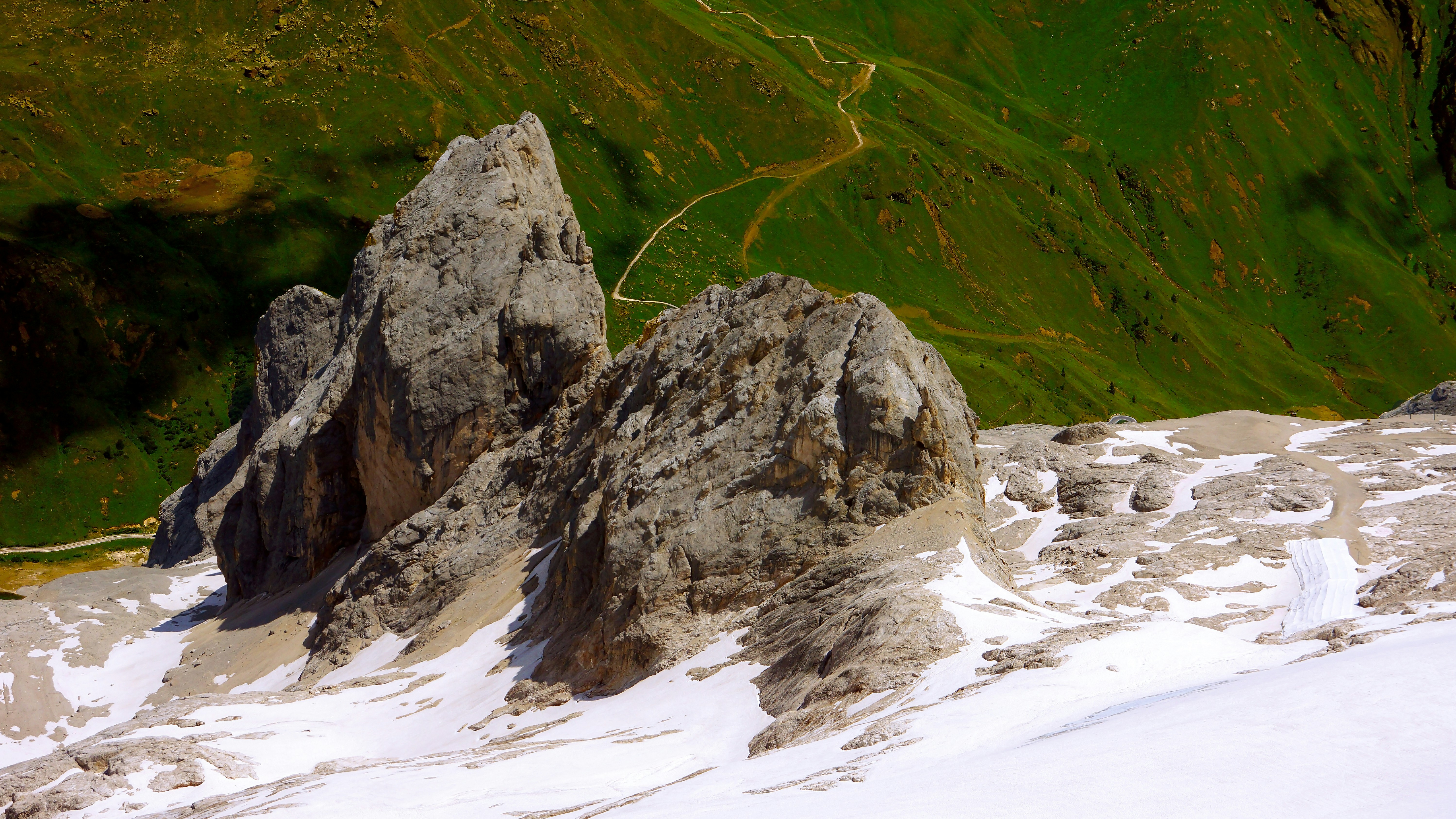 a group of mountains covered in snow next to a green hillside