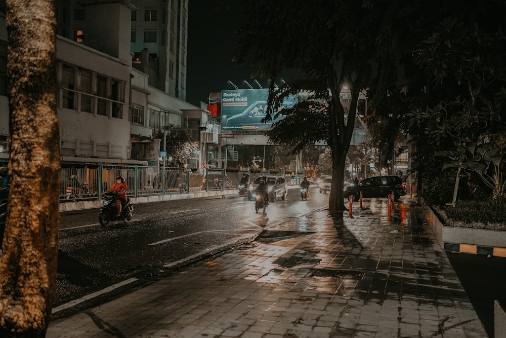 a group of people riding motorcycles down a rain soaked street