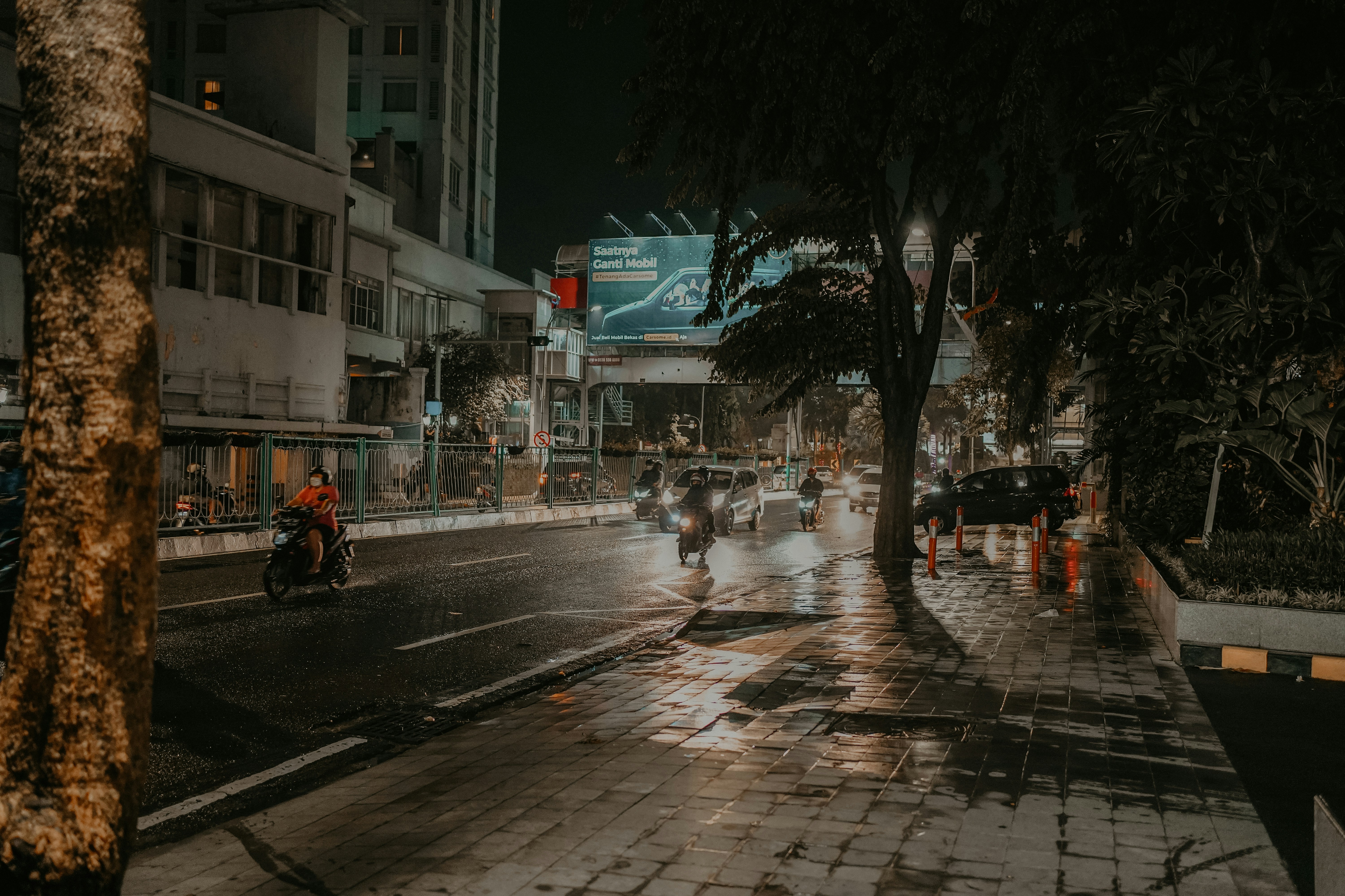 a group of people riding motorcycles down a rain soaked street