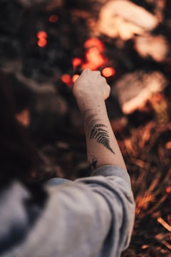 Brightly colored phoenix tattoo glowing on upper arm under natural light.