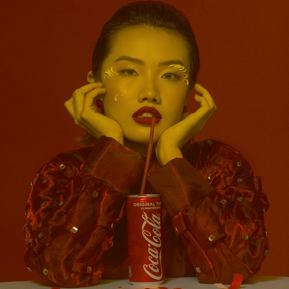 a woman with a coca cola can in front of her face